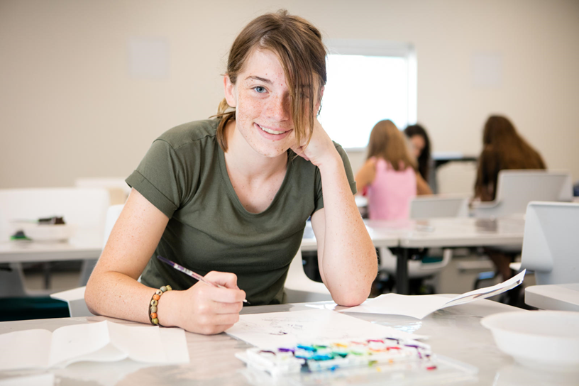 girl in green shirt sitting at desk