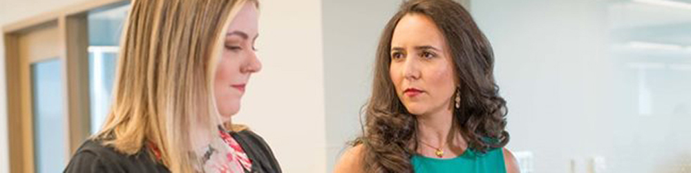 Two women in an open area of a business office