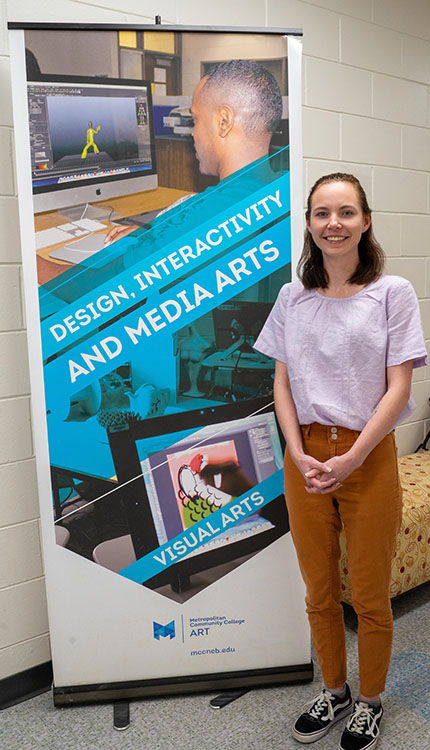 Claire Pape at Elkhorn Valley Campus standing in front of Digital Interactive Media Arts program sign